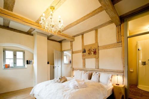 une chambre avec un grand lit blanc avec un lustre dans l'établissement allio - das turmchalet, à Berching