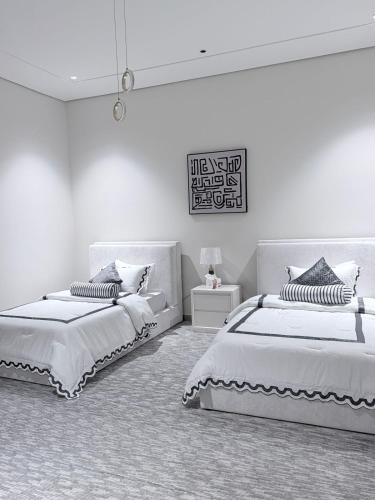 two beds in a room with white walls at منتجع دارك in Hail