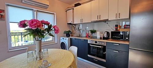 Una cocina con una mesa con un jarrón de flores encima. en AmurResidence S46 Sauna -parcare privata- 3 camere, en Iaşi
