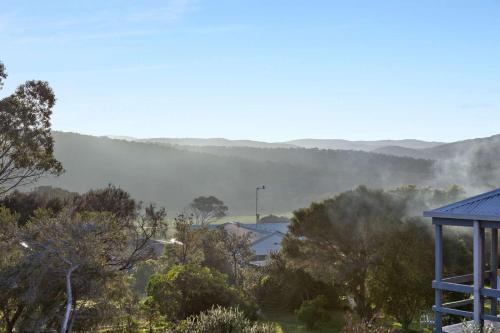 vistas a un valle nublado con árboles y una casa en Idyllic Aireys Retreat - where ocean & hills meet, en Aireys Inlet