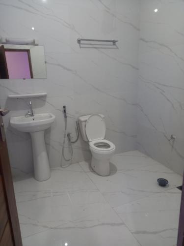 ein weißes Badezimmer mit Toilette und Waschbecken in der Unterkunft Fèmi in Rufisque