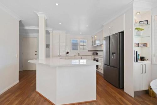 a white kitchen with a white counter top and a refrigerator at Wave Whisperer in Kingscliff
