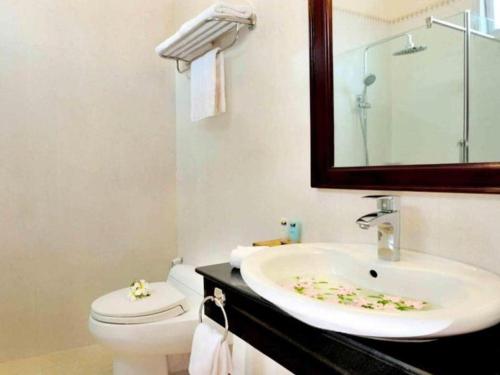 une salle de bain avec un lavabo, des toilettes et un miroir dans l'établissement Sa Huynh Resort Quang Ngai, à Sa Huynh