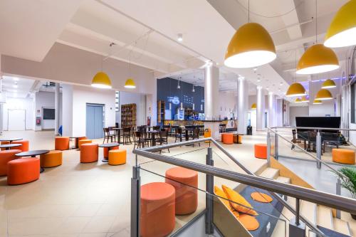 a lobby with orange chairs and tables in a building at a&o Salzburg Hauptbahnhof in Salzburg