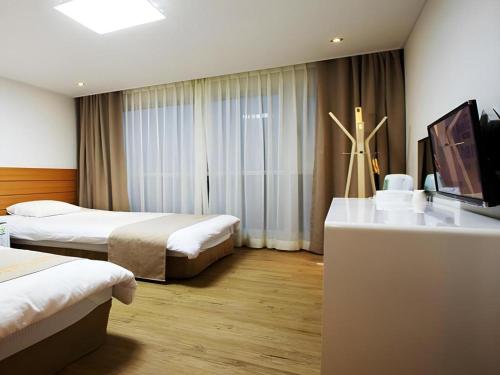 a hotel room with two beds and a flat screen tv at Ewha Hotel in Jeju