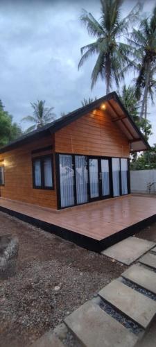 Oreo Beach Villa Kayangan في Luhuk: منزل صغير مع شرفة خشبية كبيرة