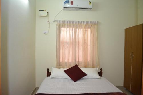 1 dormitorio con 1 cama y ventana en JP Nivaas Guest House en Mayiladuthurai
