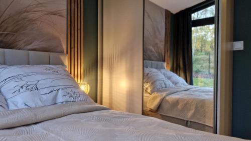 a bedroom with a mirror with a bed and a window at Domek z widokiem Wilczy Jar in Jarnołtówek