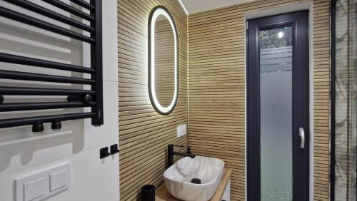 a bathroom with a wooden wall with a trash can at Domek z widokiem Wilczy Jar in Jarnołtówek