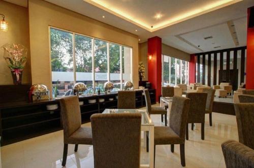 a restaurant with tables and chairs and a large window at Hotel Betha Subang in Subang