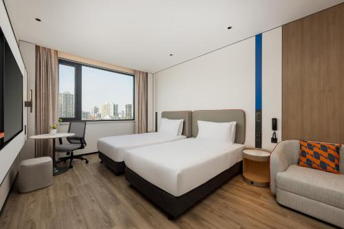 a hotel room with two beds and a couch at Holiday Inn Express Shanghai Changyang Road by IHG in Shanghai