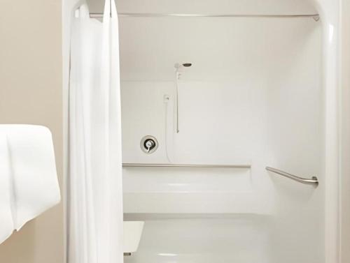a white bathroom with a shower and a white curtain at Days Inn Springfield South in Springfield