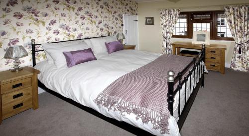 a bedroom with a large bed with purple pillows at Rose Cottage in Lincoln