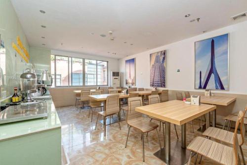 Un restaurante con mesas y sillas de madera y ventanas. en City Comfort Inn Guangzhou Baiyun Moutain Yongtai Metro Station, en Guangzhou