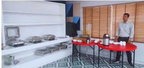 een man staat naast een rode tafel in een keuken bij Hotel Shaktiheritage Inn in Bhubaneshwar