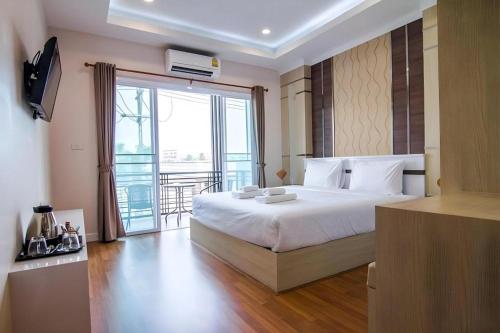 a bedroom with a large white bed and a balcony at At Home at Udon in Udon Thani