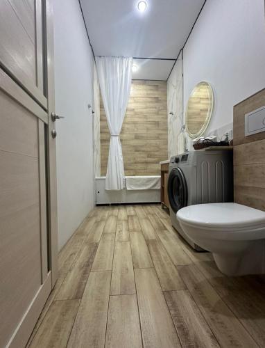 a bathroom with a toilet and a washing machine at Уютная и комфортная 3х комнатная в новом центре in Oral
