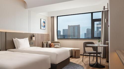 a hotel room with two beds and a table and a window at Holiday Inn Express Putian City Center in Putian