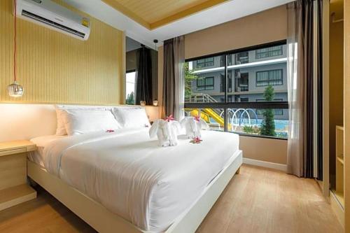 dos animales de peluche sentados en una cama en un dormitorio en Hinn - Namm Hotel, en Hua Hin