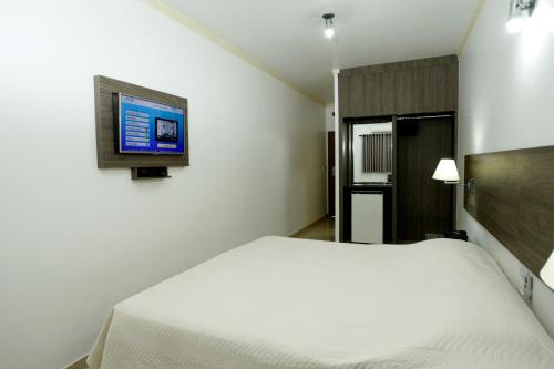 a bedroom with a bed and a tv on the wall at Hotel Match Point in São Carlos