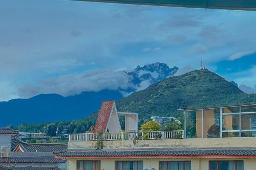 a house with a mountain in the background at 夕露小榭南门机场大巴店Xiluxiaoxie MUXIN INN in Lijiang