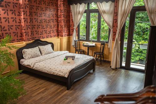a bedroom with a bed and a table and windows at Nàng Homestay Studio in Thu Dau Mot