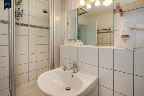 a white bathroom with a sink and a mirror at Waldsiedlung Waldhaus App 4.2 in Korswandt