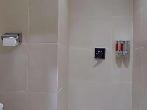 un mur carrelé blanc dans une salle de bain avec toilettes dans l'établissement Tropical Point Hotel Syariah, à Pipulu