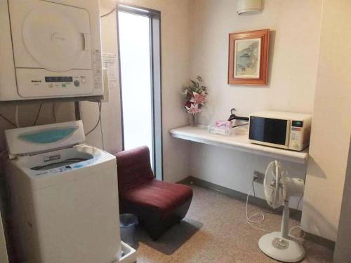 a small room with a microwave and a chair at Sento Otani Hotel in Toyooka