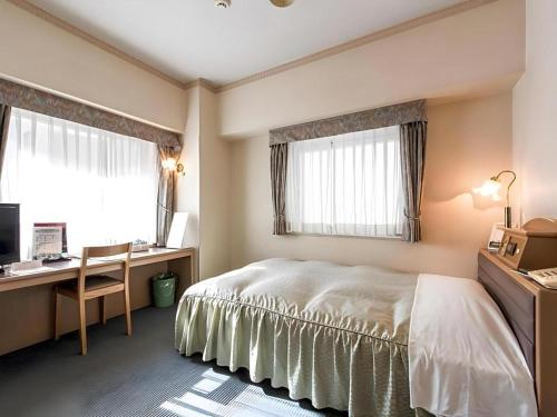 une chambre avec un lit, un bureau et des fenêtres dans l'établissement Hotel Starplaza Ikebukuro, à Tokyo