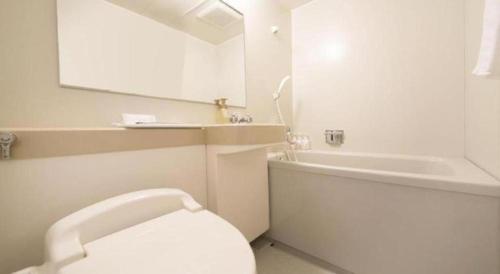 a bathroom with a white toilet and a bath tub at Kamikochi Taishoike Hotel in Matsumoto