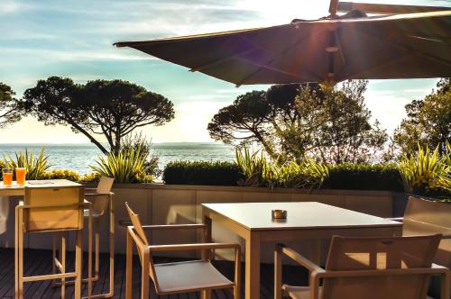 a patio with tables and chairs and an umbrella at Hotel Corte Valier in Lazise