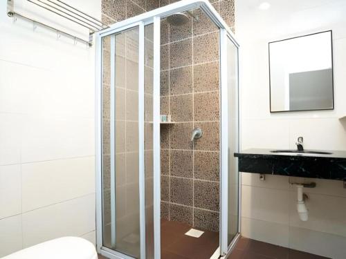 ジョホールバルにあるS Bee Hotelのガラスのシャワーと洗面台を備えたバスルーム