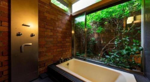 une baignoire dans une salle de bain avec une grande fenêtre dans l'établissement Auberge Tosayama, à Kawaguchi