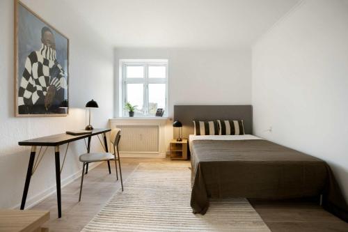 a bedroom with a bed and a table and a desk at Valby family apartment in Copenhagen