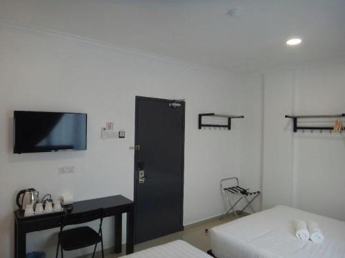 a room with two beds and a tv on the wall at Hotel Seri Geliga in Kampong Geliga Besar