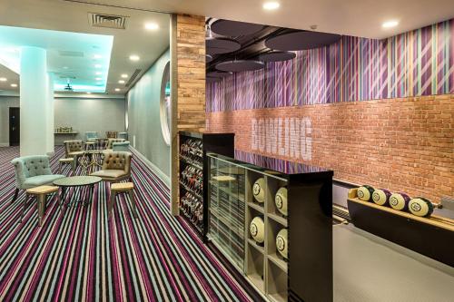 a waiting area with chairs and tables and a brick wall at Courthouse Hotel Shoreditch in London