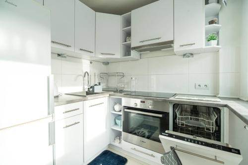 a white kitchen with white cabinets and an oven at Apartly - Apartament Wyszyńskiego z loggią in Szczecin
