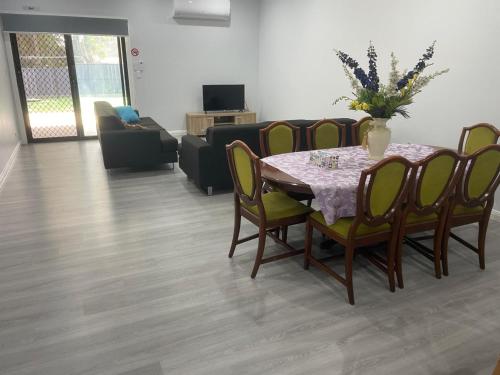 Una sala de estar con una mesa y sillas y un sofá. en Quiet Spacious Family House, en Rooty Hill