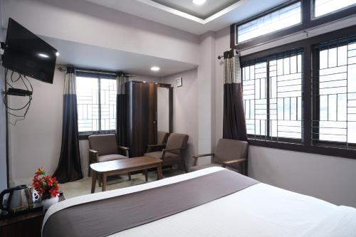 a hotel room with a bed and a table and chairs at Shiva Guest House in Guwahati