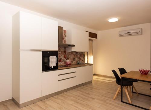 a kitchen with white cabinets and a table with chairs at Il Nido dei Merli in Fiumicino