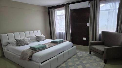 a bedroom with a white bed with a chair and a window at 112 on Park Drive in Port Elizabeth