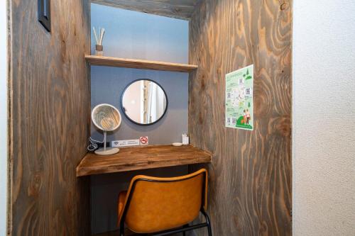 een spiegel en een stoel in een kamer bij Guest House NANMO in Minami-jūichijō