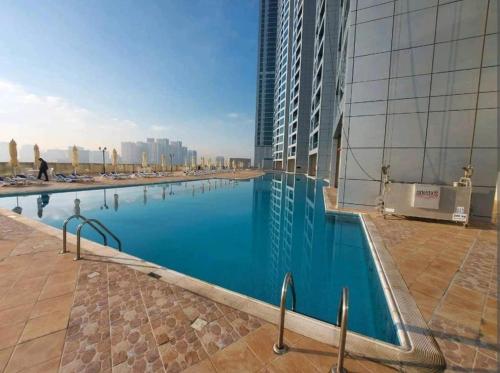 a large swimming pool next to a tall building at Spacious 3BR Seaview Duplex Perfect for Families in Ajman