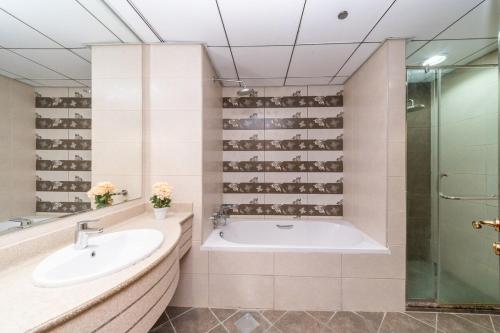 a bathroom with a tub and a sink and a shower at Spacious 3BR Seaview Duplex Perfect for Families in Ajman 