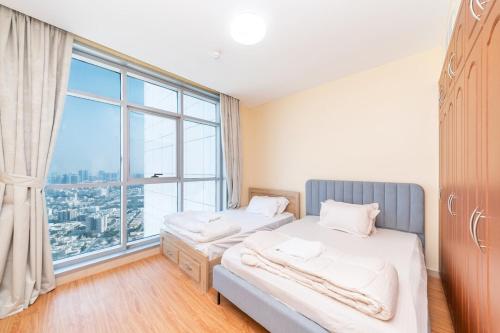 two beds in a room with a large window at Spacious 3BR Seaview Duplex Perfect for Families in Ajman 