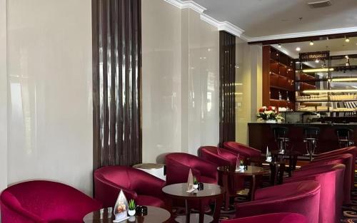 チラチャプにあるSindoro Hotel Cilacap By Conaryの赤い椅子とテーブル、バーがあるレストラン