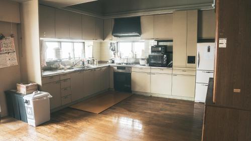 a large kitchen with white appliances and wooden floors at Kamui Kids House