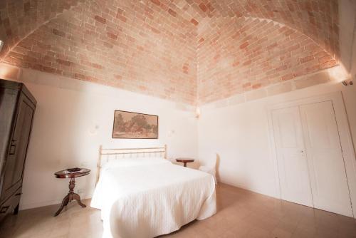 a bedroom with a white bed and a brick wall at La Casa di Ele in Matera
