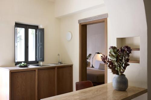 a kitchen with a table with a vase of flowers on it at Bellonias Villas in Kamari